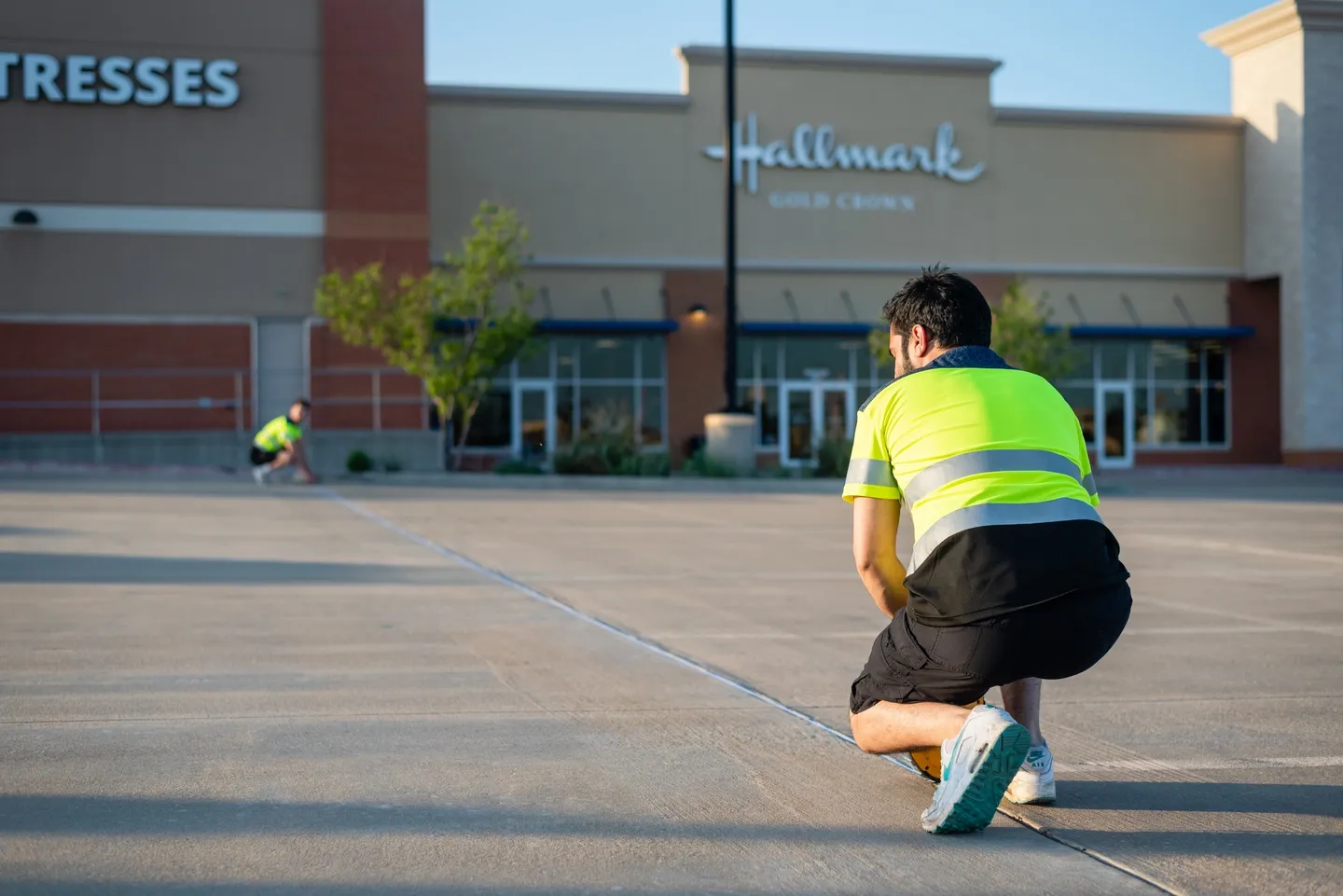 Two people doing a parking lot striping project